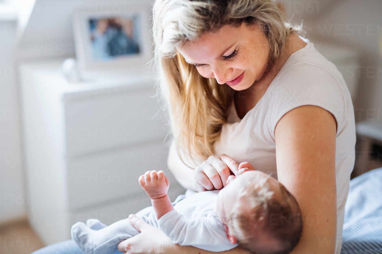 a beautiful young mother holding a newborn baby at home.